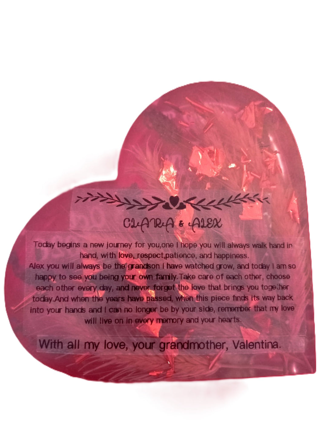 Reverso de un corazón artesanal de resina rosa con la dedicatoria en inglés de la abuela Valentina para Clara y Alex
